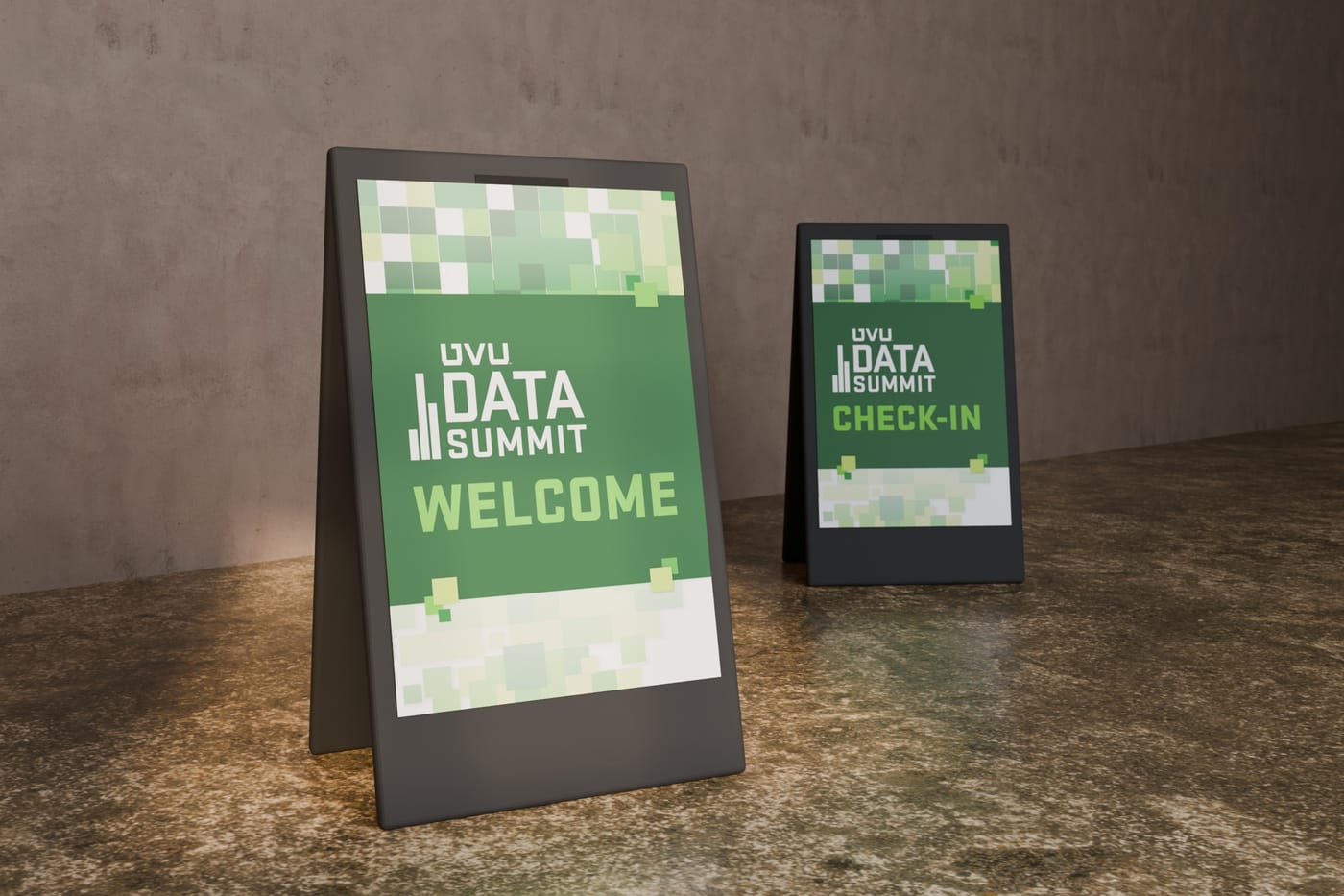 Two Data Summit A-frame signs on a concrete floor, Welcome in front and Check-In behind, each banded with green pixel squares.