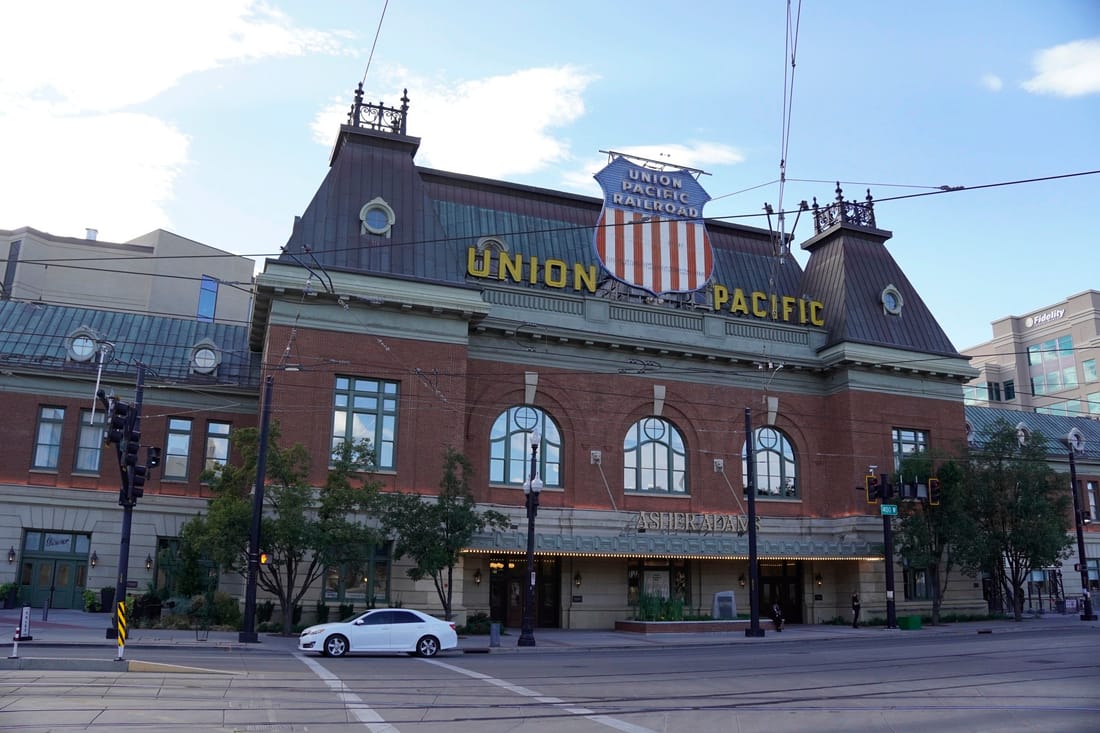 The brick Union Pacific depot with its shield-shaped sign and mansard roof, seen across the street.