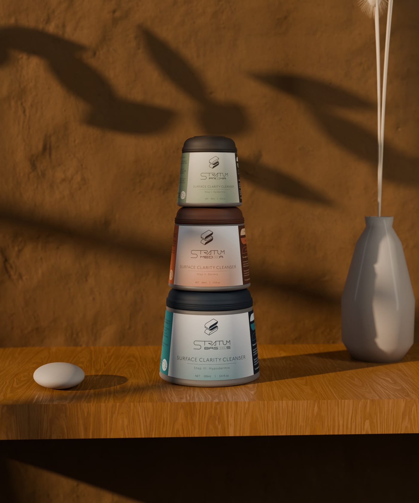 The three Stratum jars stacked on an oak shelf in low evening sun, leaf shadows on a warm plaster wall, a bud vase of dried grass and a smooth stone beside them.